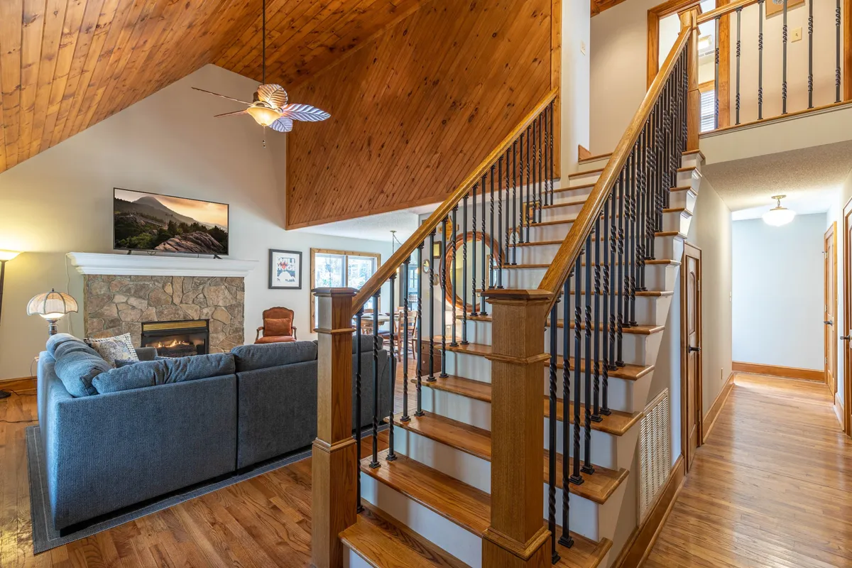 A comfortable living area featuring a plush sofa, fireplace, staircase, and television. The setting is ideal for relaxing evenings after outdoor activities, with plenty of space for dogs to nap or join in family gatherings.