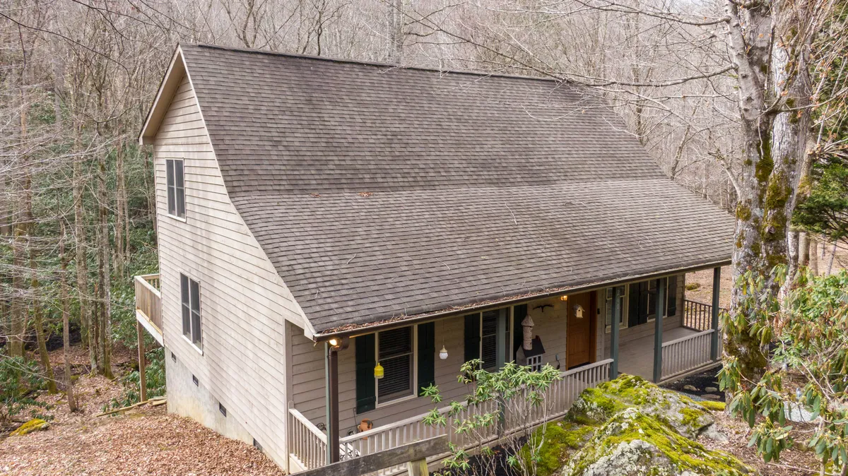 This image features the house nestled among trees, showcasing a peaceful porch area and the serene wooded setting. The inviting porch and the natural surroundings suggest a restful retreat, ideal for returning from a day of local exploration.